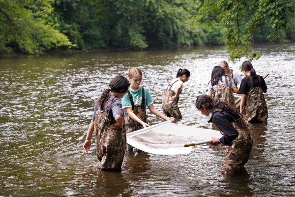 Girls collecting and analyzing river silt samples at Summer in Farmington